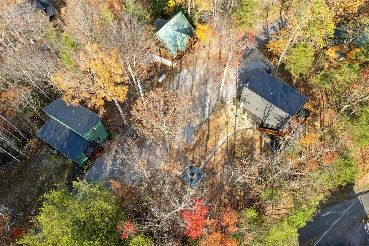 This image captures a tranquil Smoky Mountain landscape in autumn, with colorful leaves blanketing the hills and several scattered cabins nestled among the trees. A winding path invites viewers to imagine hiking or taking nature walks, while the broad scene evokes the expanse and proximity of mountain adventures.