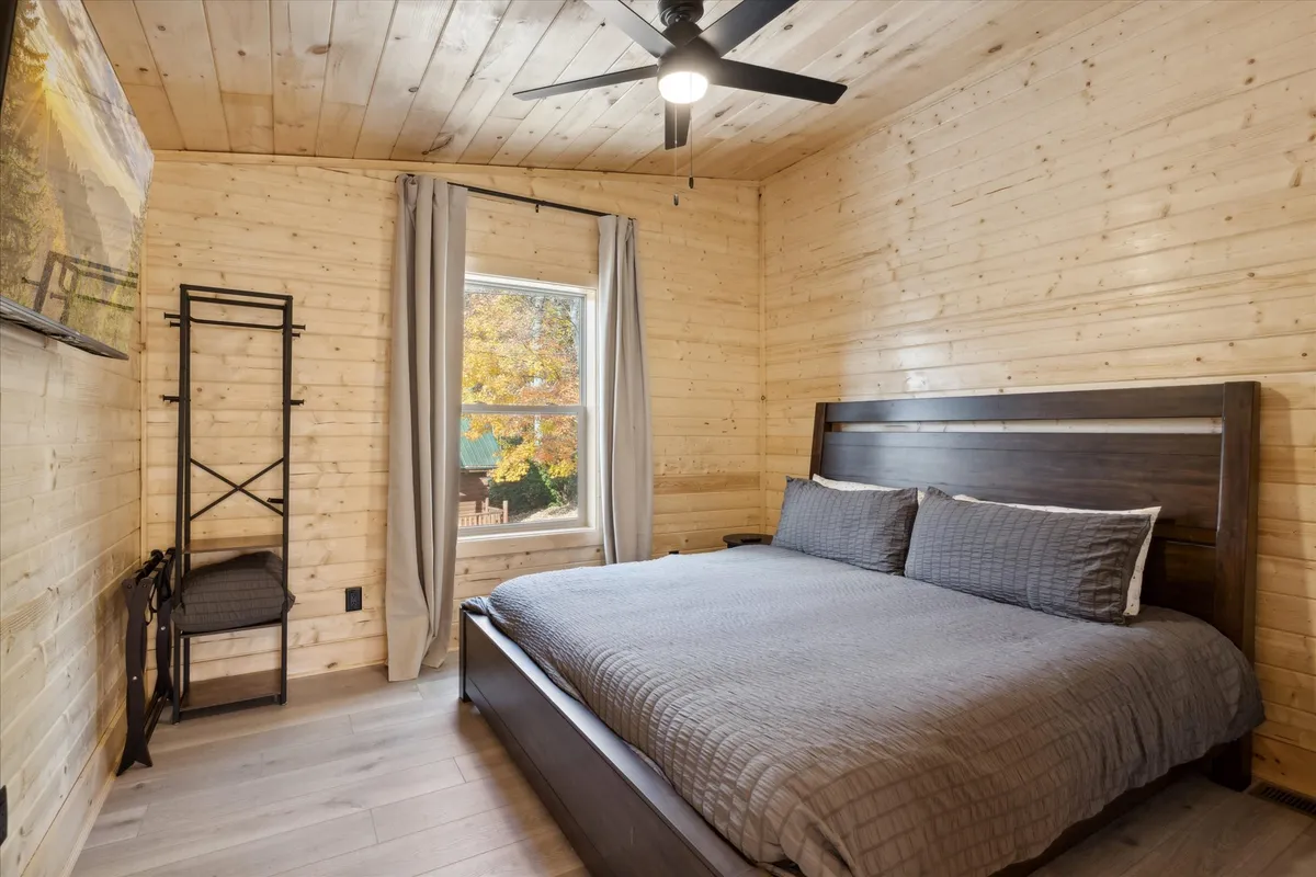 A serene king bedroom with a large, inviting bed as the focal point. Natural light streams in through a window, highlighting tasteful wall art and a minimalist shelf, creating a calming retreat for relaxation or rejuvenation after a busy day.