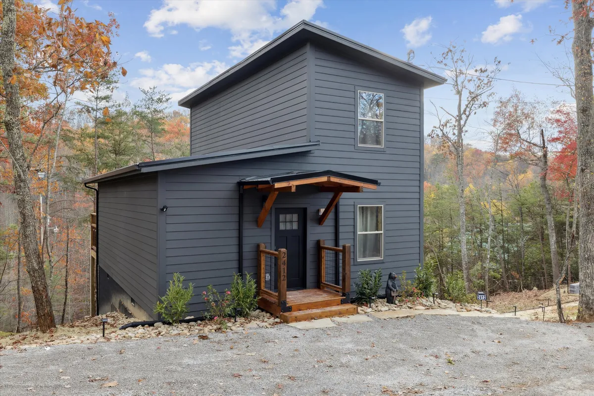 The image displays the modern, welcoming entries of the cabins with surrounding foliage and a porch area. It hints at the seamless access between indoor and outdoor spaces and showcases the environment that frames the courtyard.